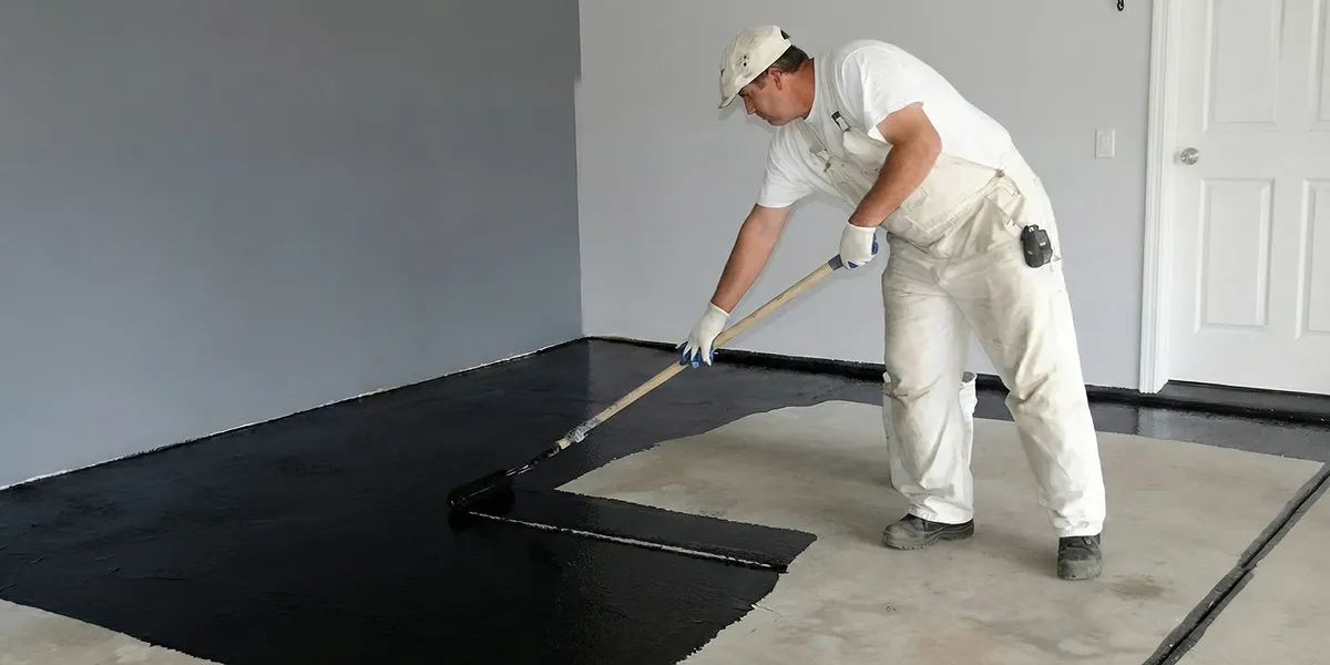 basement waterproofing professional applying waterproof coating to protect a basement floor in Houston, TX